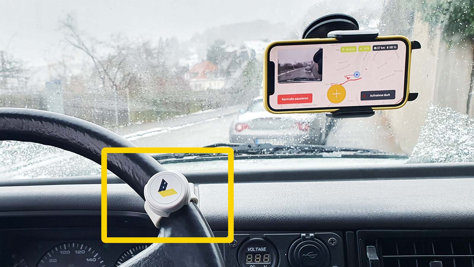 A smartphone with the vialytics system opened in a holder on the windshield and the marker tool on the steering wheel