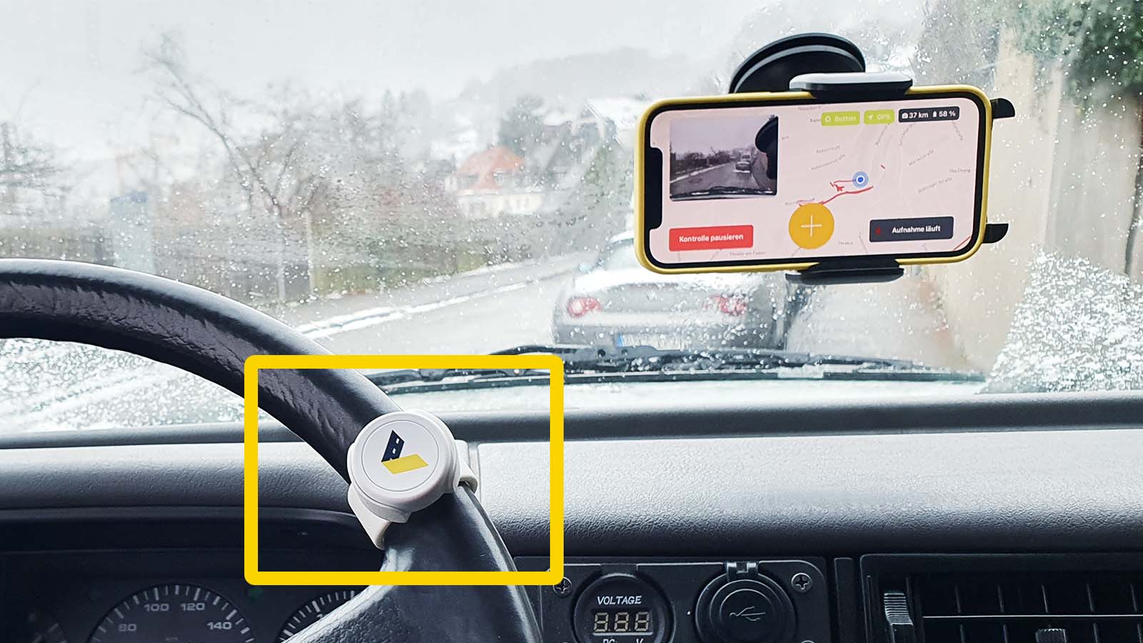 A smartphone with the vialytics system opened in a holder on the windshield and the marker tool on the steering wheel