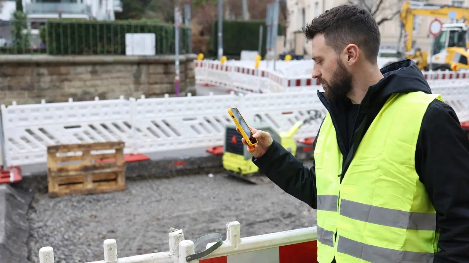 Un technicien de terrain enregistre les défauts sous garantie sur un chantier à l'aide de son smartphone