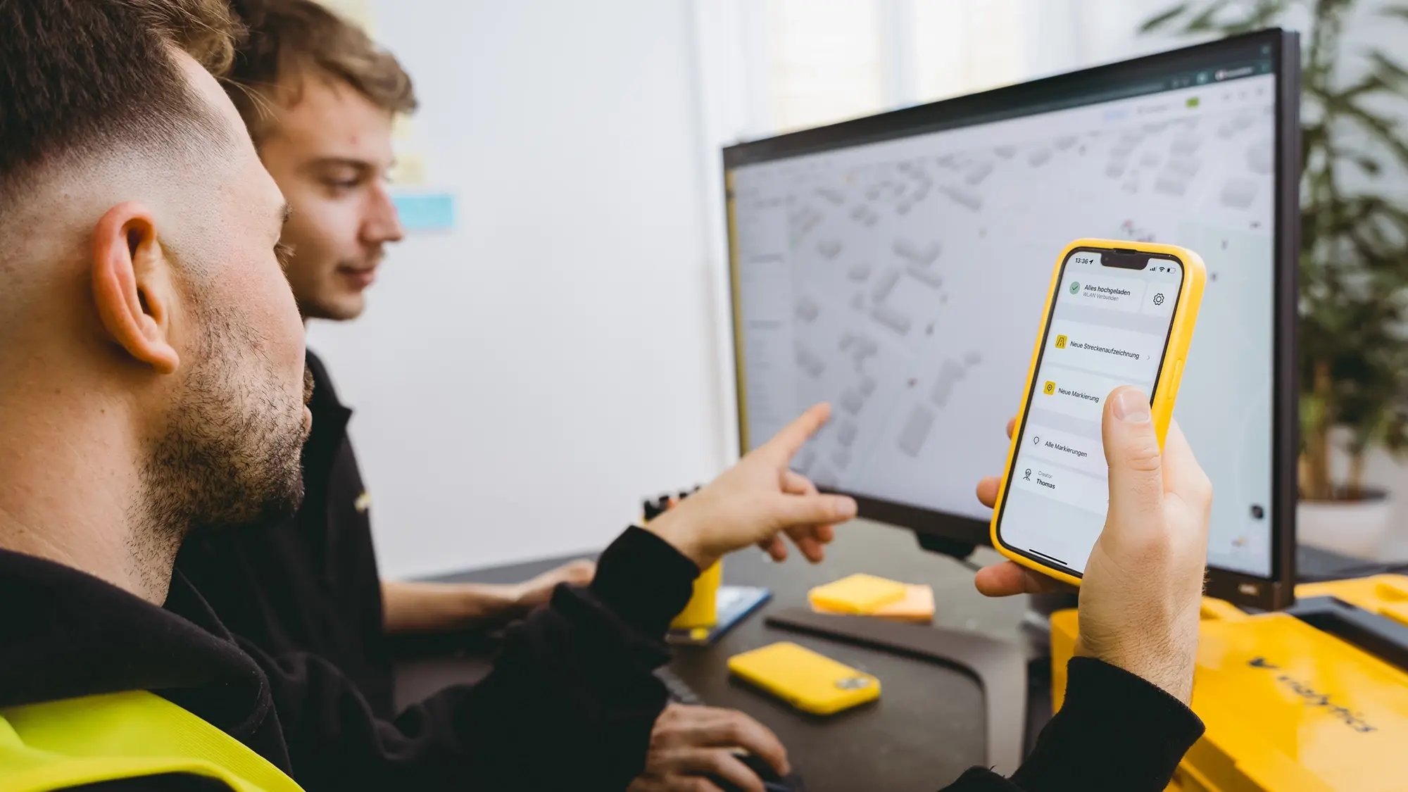 Deux collaborateurs examinent et traitent ensemble les cas de garantie sur leur ordinateur et leur smartphone.