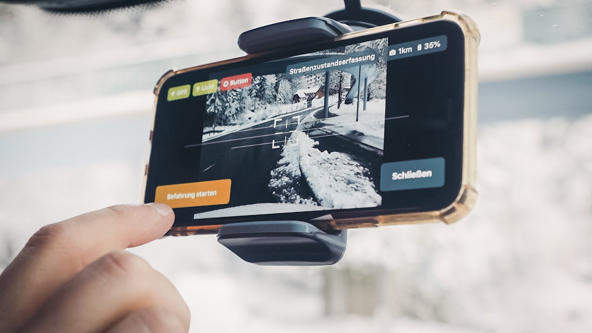 A cell phone in a holder with the vialytics system open hanging on a windshield
